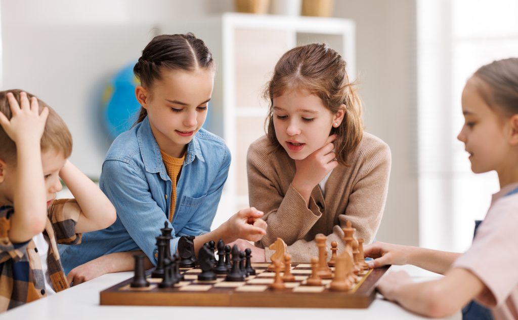 Children gathered around a chessboard during a fun educational chess activity
